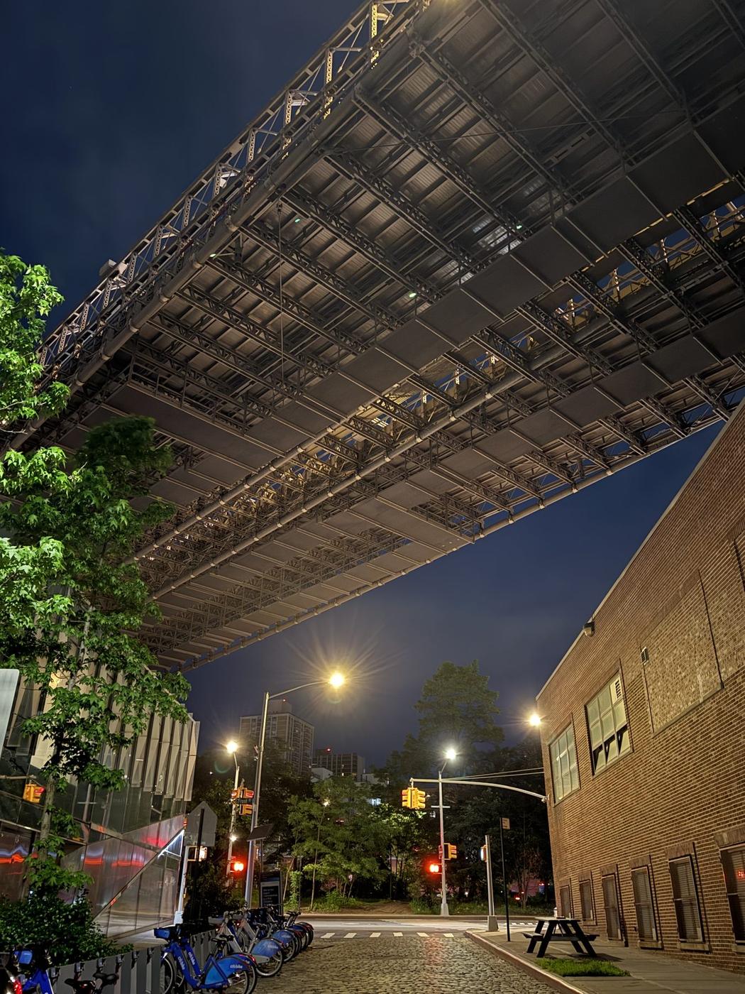 City street at night beneath an elevated rail structure